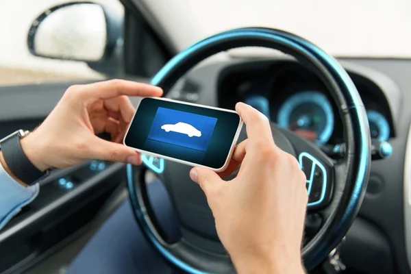 Close up of male hands with car icon on smartphone — ストック写真