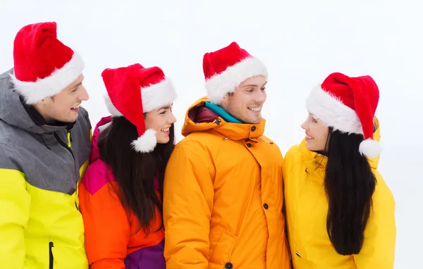Szczęśliwy przyjaciół w santa kapelusze i Ubiory narciarskie na zewnątrz — Zdjęcie stockowe