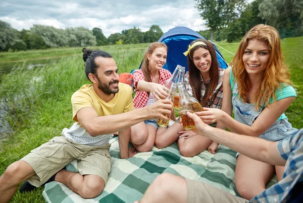 Amici felici con tenda e bevande al campeggio — Foto Stock