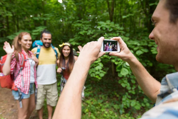 Happy man photographing friends by smartphone — ストック写真