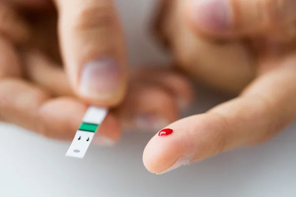 Primo piano del dito maschile con sangue e striscia di prova — Foto Stock