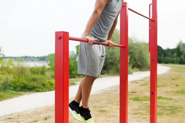 young man exercising on horizontal bar outdoors