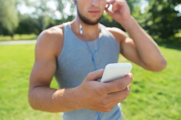 Junger Mann mit Kopfhörern und Smartphone im Park — Stockfoto