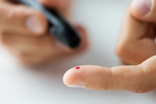 Nahaufnahme des männlichen Fingers mit Blut und Glukometer — Stockfoto