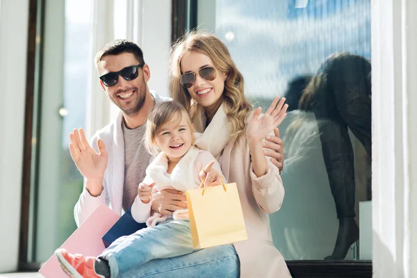 happy family with child and shopping bags in city