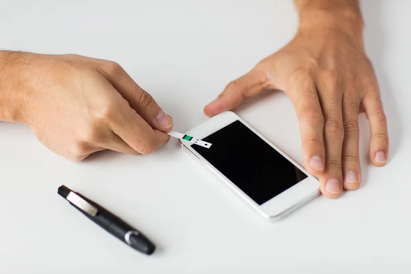 Close-up de homem com smartphone fazendo teste de sangue — Fotografia de Stock