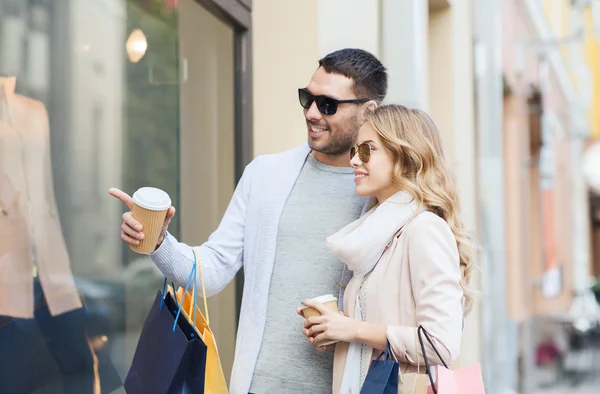 Happy couple with shopping bags and coffee in city — Stock Photo, Image