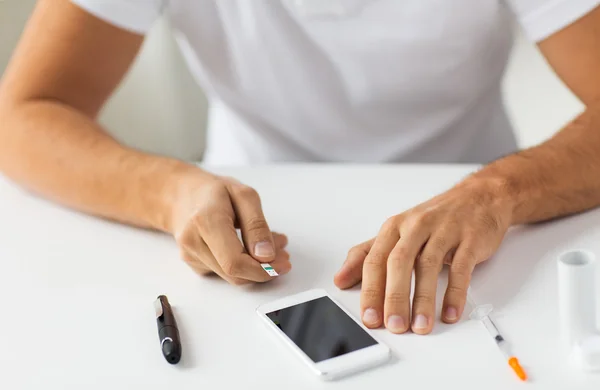 Крупним планом чоловік зі смартфоном, що робить аналіз крові — стокове фото