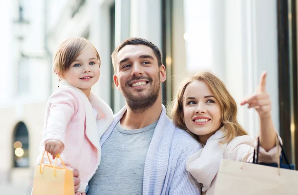 Mutlu aile çocuk ve şehirde alışveriş torbaları — Stok fotoğraf