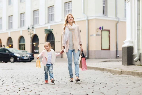 Happy mother and child with shopping bags in city — Stock Photo, Image