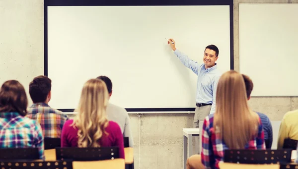 Grupp studenter och leende lärare i klassrummet — Stockfoto