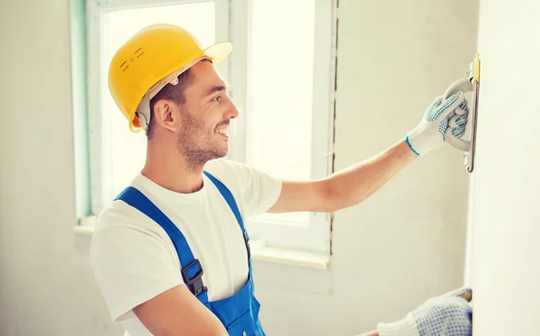 Lächelnder Bauarbeiter mit Schleifwerkzeug im Haus — Stockfoto