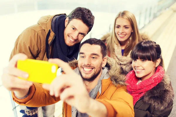 Amici felici con smartphone sulla pista di pattinaggio — Foto Stock