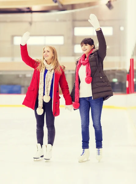Ragazze felici amici che agitano le mani sulla pista di pattinaggio — Foto Stock
