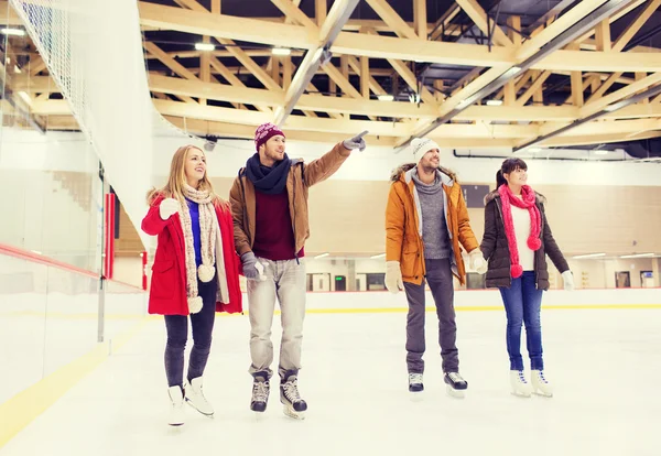 Happy friends pointing finger on skating rink — Stock Photo, Image