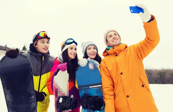 Happy friends with snowboards and smartphone — Stock Photo, Image