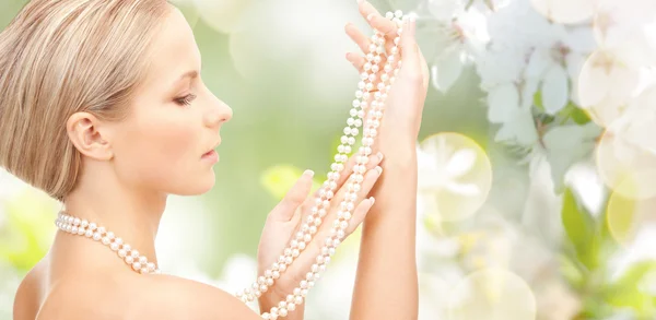 Mulher com colar de pérolas sobre flor de cereja — Fotografia de Stock