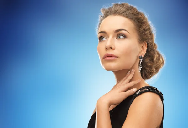 Hermosa mujer con pendientes sobre azul — Foto de Stock