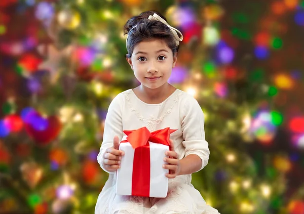 Niña feliz con presente sobre las luces — Foto de Stock