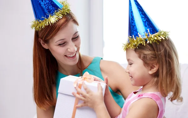 Feliz madre e hijo en gorras de fiesta con caja de regalo — Foto de Stock