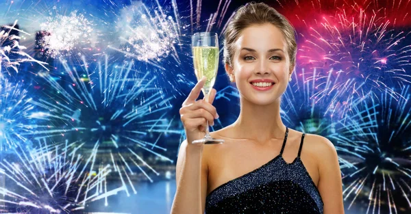 Femme heureuse avec verre de champagne sur le feu d'artifice Image En Vente
