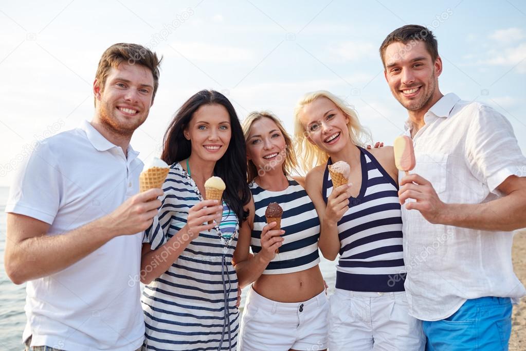 Smiling friends eating ice cream on beach Stock Photo by ©Syda