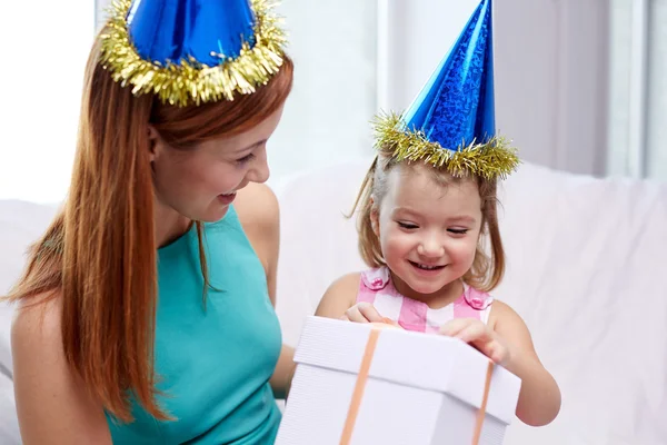 Feliz madre e hijo en gorras de fiesta con caja de regalo — Foto de Stock