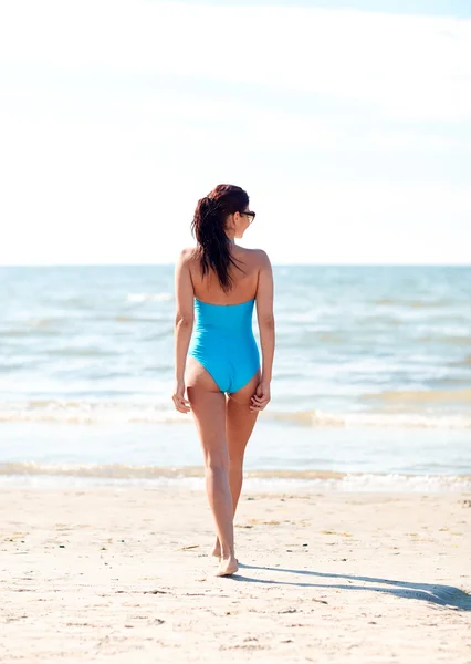 Νεαρή γυναίκα με μαγιό περπάτημα στην παραλία — Φωτογραφία Αρχείου
