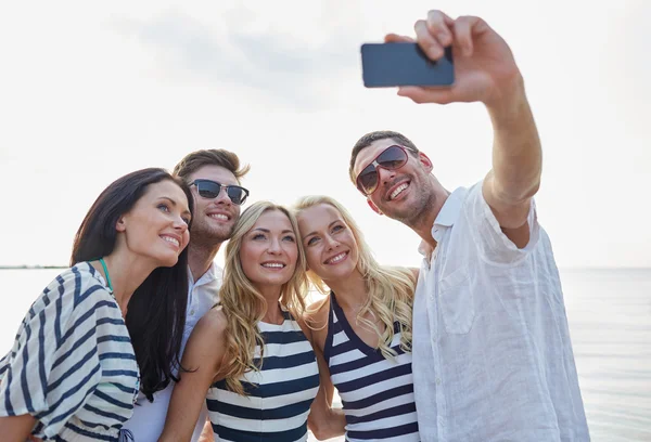 Happy friends on beach and taking selfie Stock Image