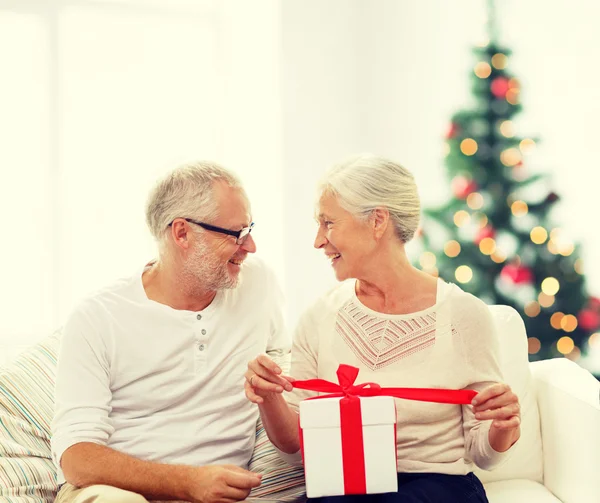 Happy senior couple with gift box at home — Stock Photo, Image