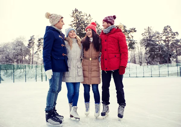 Happy přátelé bruslení na kluzišti venku — Stock fotografie