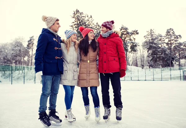 Amigos felices patinaje sobre hielo en pista al aire libre —  Fotos de Stock