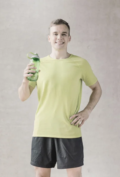 Улыбающийся мужчина с бутылкой воды в тренажерном зале — стоковое фото