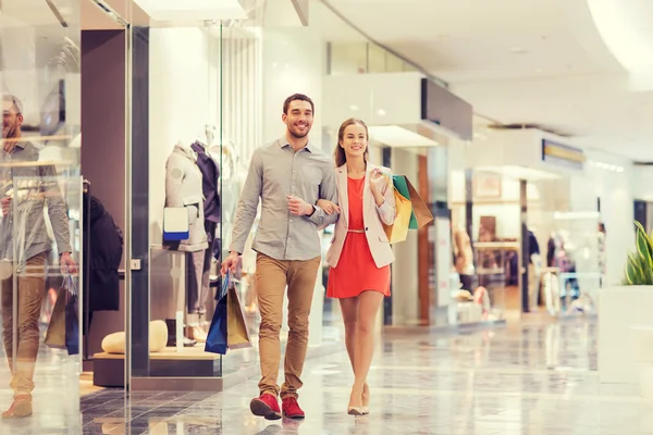 Feliz pareja joven con bolsas de compras en el centro comercial —  Fotos de Stock