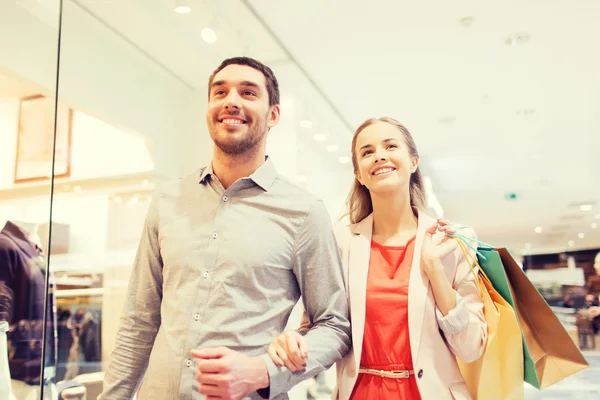 Feliz jovem casal com sacos de compras no shopping — Fotografia de Stock