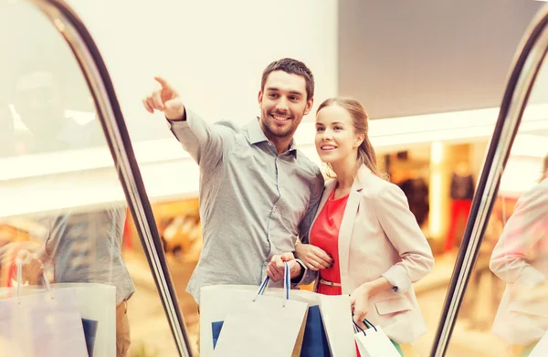 Feliz jovem casal com sacos de compras no shopping — Fotografia de Stock