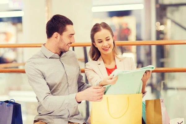 Feliz jovem casal com sacos de compras no shopping — Fotografia de Stock