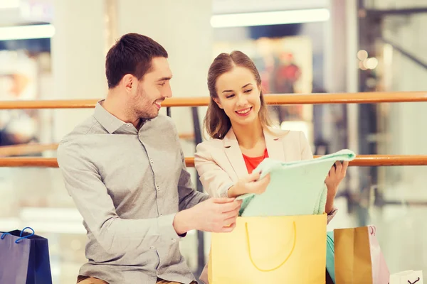 Happy young couple with shopping bags in mall — Stock Photo, Image