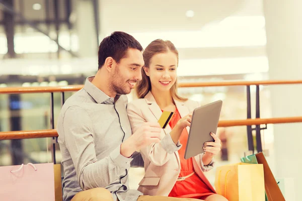 Couple with tablet pc and shopping bags in mall — Stock Photo, Image