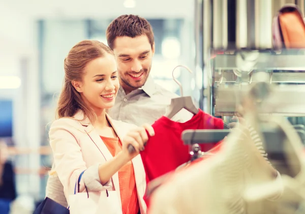 Happy young couple choosing dress in mall — Stock Photo, Image