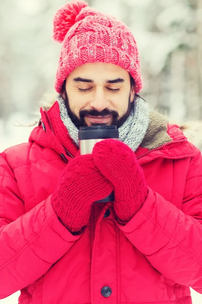 Lächelnder junger Mann mit Tasse im Winterwald — Stockfoto