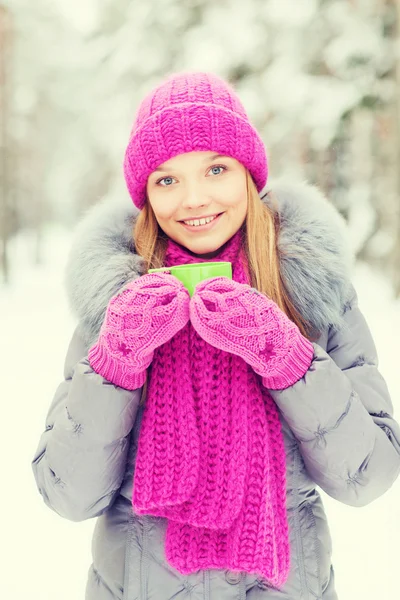 Sonriente joven con taza en el bosque de invierno — Foto de Stock