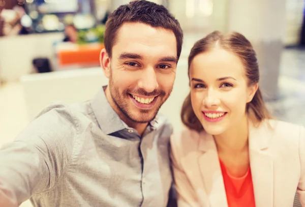 Feliz pareja tomando selfie en centro comercial u oficina — Foto de Stock