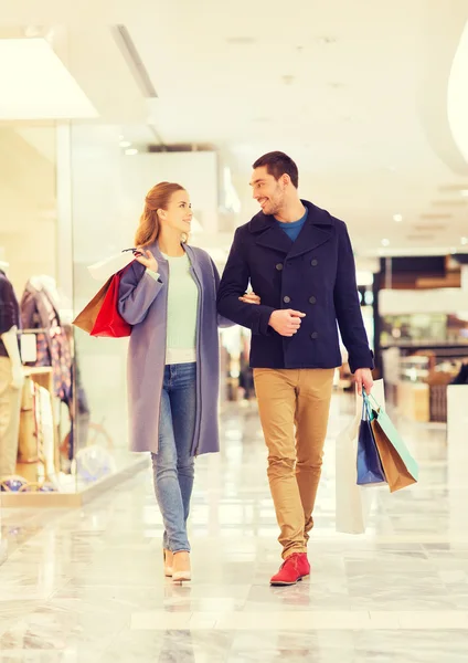 Feliz jovem casal com sacos de compras no shopping — Fotografia de Stock