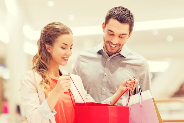 Feliz jovem casal com sacos de compras no shopping — Fotografia de Stock