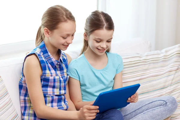 Gelukkig meisjes met tablet pc zitten op bank thuis — Stockfoto