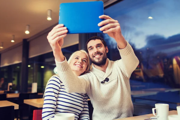 Gelukkige paar met tablet pc nemen selfie in café — Stockfoto