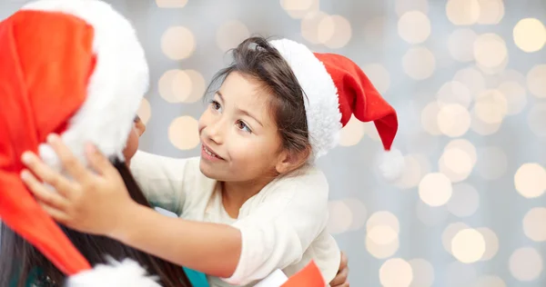 Glückliche Mutter und kleines Mädchen in Weihnachtsmützen — Stockfoto