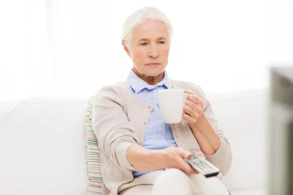 Anziana donna guardando la tv e bevendo tè a casa — Foto Stock