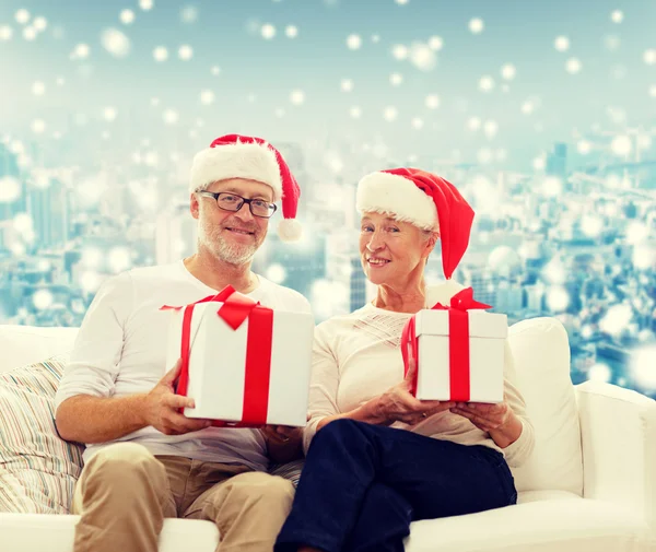 Glückliches Seniorenpaar in Weihnachtsmützen mit Geschenkschachteln Stockbild